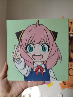 a person holding up a painting with an anime character on it's face and pointing to the side