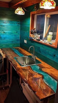 a kitchen counter made out of wood with a sink in the center and two stained glass windows above it