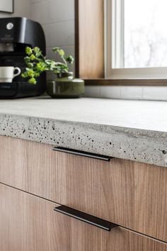 a kitchen counter top with black handles and a coffee maker in the backgrouund