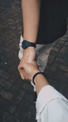 two people holding hands while walking down the street