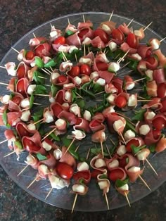 skewered meats and vegetables are arranged in a circle on a clear plate