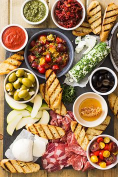 an assortment of meats and cheeses on a platter with breadsticks