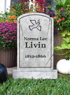 a headstone sits in the grass next to potted plants