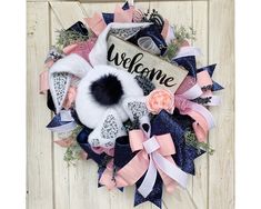 a welcome wreath on the front door with pink, blue and white ribbons around it