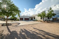 a large house sitting in the middle of a dirt lot next to trees and bushes