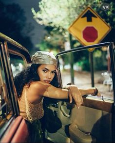 a woman leaning out the window of a car with her hand on the door handle