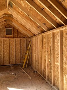 an attic with wooden framing and ladders in the room that is being built into the wall