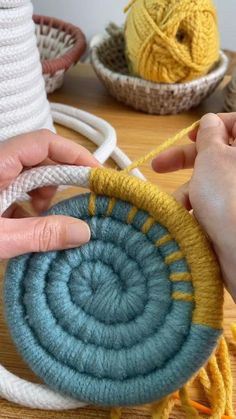 someone crocheting yarn on top of a blue and yellow piece of cloth in front of two bowls