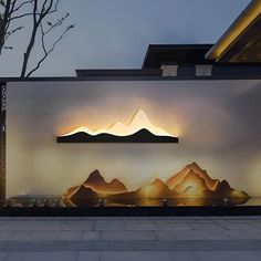 a wall that has some lights on it in front of a building with mountains painted on it