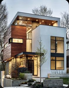 a modern house with lots of windows and lights on the front door is shown in this photo