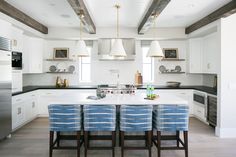 a kitchen with white cabinets and blue chairs