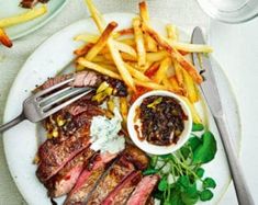 steak and french fries on a plate with sauces next to the plate is a fork