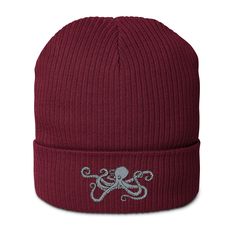 an octopus embroidered on a maroon knit beanie hat with silver thread work in the center