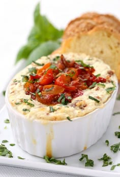 a close up of a bowl of food on a plate with bread in the background