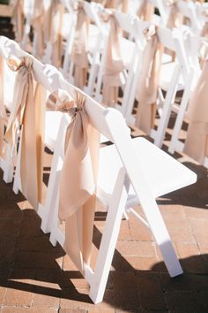 rows of white folding chairs with bows tied to them