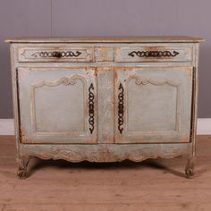 an old white painted cabinet with ornate carvings on the front and sides, against a gray wall