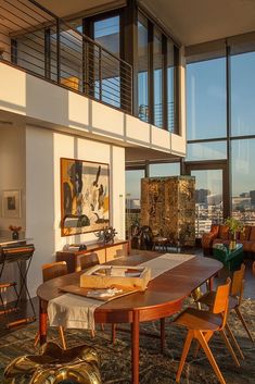 a dining room table and chairs in front of large windows overlooking the cityscape