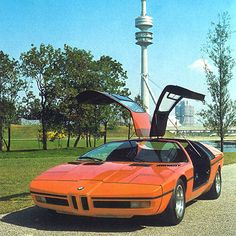 an orange sports car parked in front of a tall tower