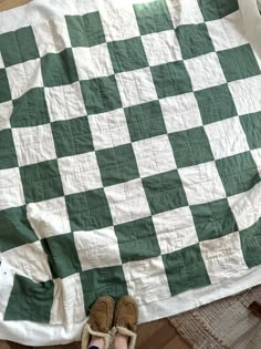 someone's feet are on top of a green and white checkerboard blanket