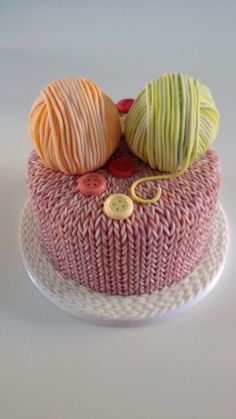 there are two balls of yarn on top of this pink and white cake with buttons