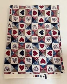 a red, white and blue patchwork quilt with hearts on the front is shown