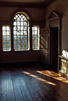 an empty room with wooden floors and large windows