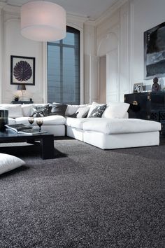 a living room filled with lots of white furniture and black rugs on the floor