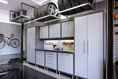 a garage with two bikes hanging from the ceiling and an overhead tire rack on the wall