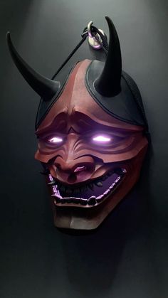 a mask with horns and glowing eyes is hanging on the wall in front of a black background