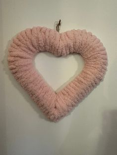 a pink heart shaped pillow hanging on the wall