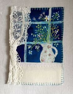 a piece of cloth with lace on it and flowers in a vase next to a window