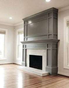 an empty living room with a fireplace and two windows