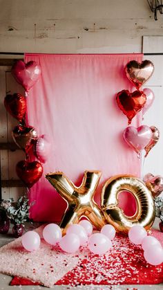 balloons and confetti are scattered on the floor in front of a pink backdrop