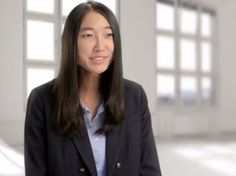 a woman standing in an empty room with white walls and windows behind her is looking at the camera