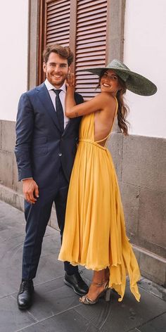 a man in a suit and tie standing next to a woman wearing a yellow dress