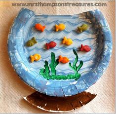 a paper plate shaped like a fish bowl with goldfish in the water on it