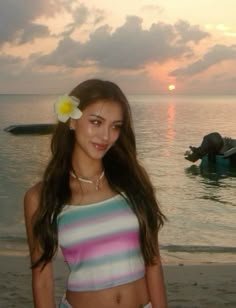 a young woman standing on top of a beach next to the ocean