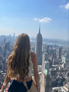 a woman standing on top of a tall building looking down at the cityscape