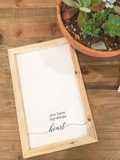 a wooden frame sitting on top of a table next to a potted plant and paper