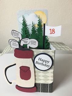 a birthday card with a golf bag and tees in the cup, on top of a table