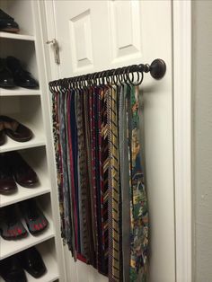 a closet filled with lots of ties hanging from the side of a white door next to a pair of shoes