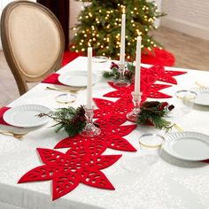 the table is set for christmas dinner with white plates and red napkins on it