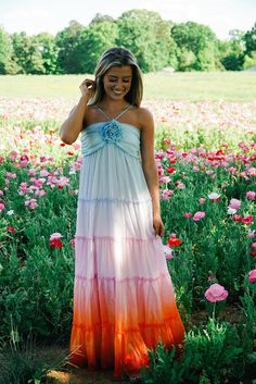 a woman standing in a field full of flowers wearing a dress with an ombrella