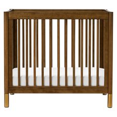 a wooden crib with white sheets in it