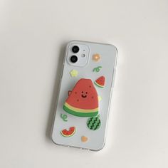 a watermelon phone case sitting on top of a white table next to an iphone