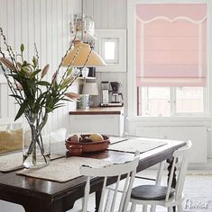 a dining room table and chairs with flowers in vases on the table next to it