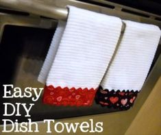 two white dish towels hanging from the side of a toaster oven with hearts on them