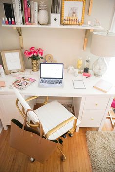 a laptop computer sitting on top of a white desk next to a chair and bookshelf