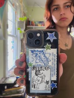 a woman holding up her phone case with stickers on it