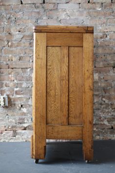 an old wooden cabinet sitting in front of a brick wall with no one around it